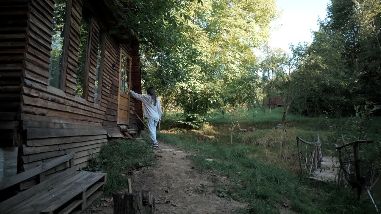 mujer entrando a una cabaña en la naturaleza, al aire libre, acampando