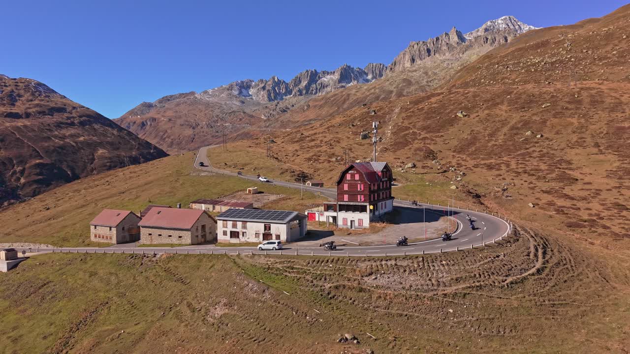 Auto sulla strada del Passo della Furka in una giornata di sole, cime sullo sfondo, vista aerea