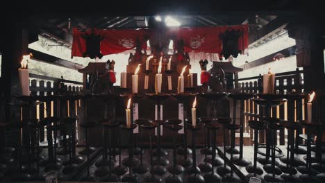 candles burning inside temple with kitsune fox statue at fushimi inari taisha shinto shrine in kyoto, japan