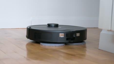 un robot aspirador autónomo gira, limpia y limpia un piso de madera en una sala de estar de la casa