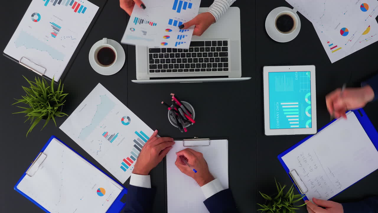 Coworkers sitting at office desk and discussing financial documents
