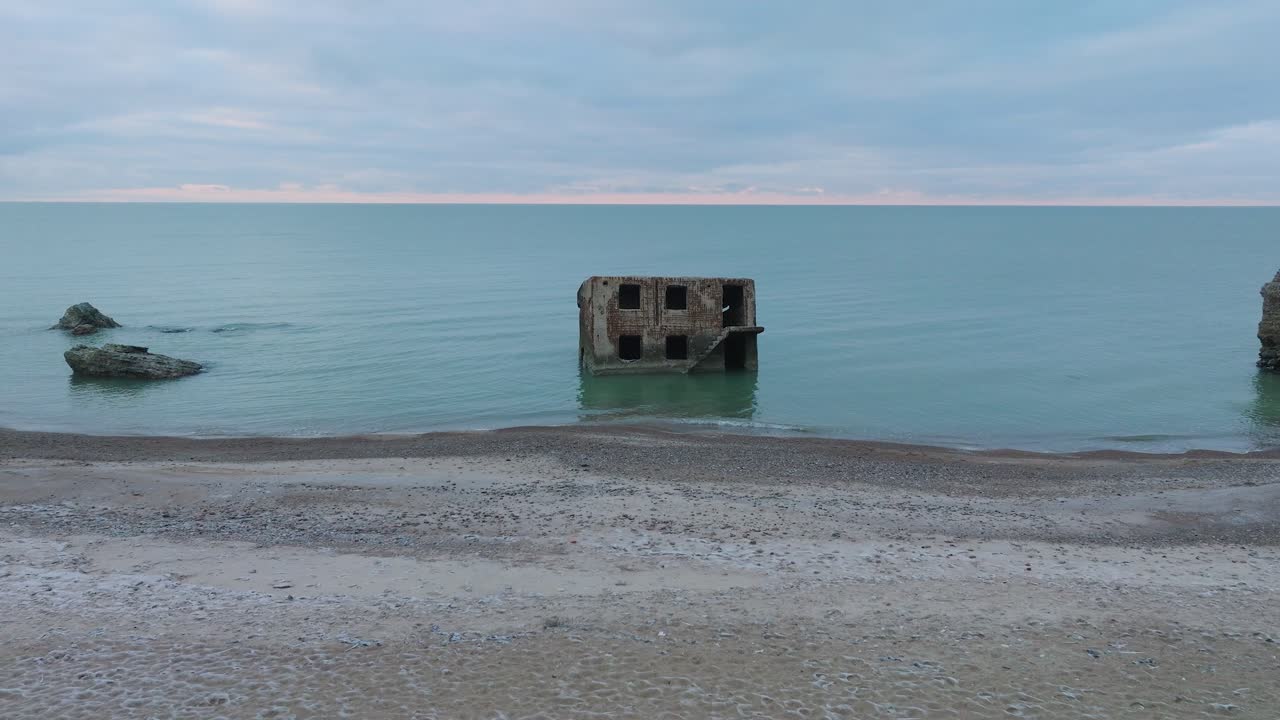 발트해 해변에 있는 카로스타 북부 요새에서 버려진 해변 요새 건물의 공중 전망을 설정하고, 흐린 날, 넓은 드론 샷이 앞으로 이동합니다.