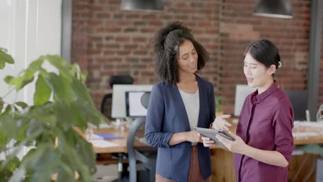 Fröhliche,-Vielfältige-Gelegenheitsgeschäftsfrauen,-Die-Ein-Tablet-Nutzen-Und-In-Zeitlupe-über-Die-Arbeit-Im-Büro-Diskutieren