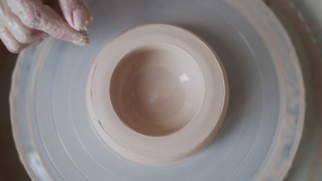 female potter makes a pot on the pottery wheel.