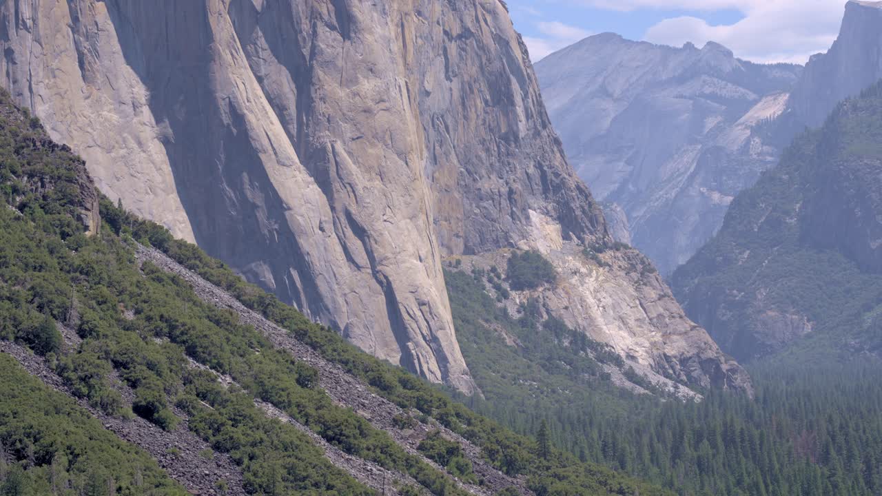 Footage showing the base of the towering granite rock face of El Capitan in Yosemite National Park, California. The scene highlights the massive, textured cliff surface.