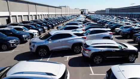 Large parking lot filled with new cars and SUVs outside a commercial building