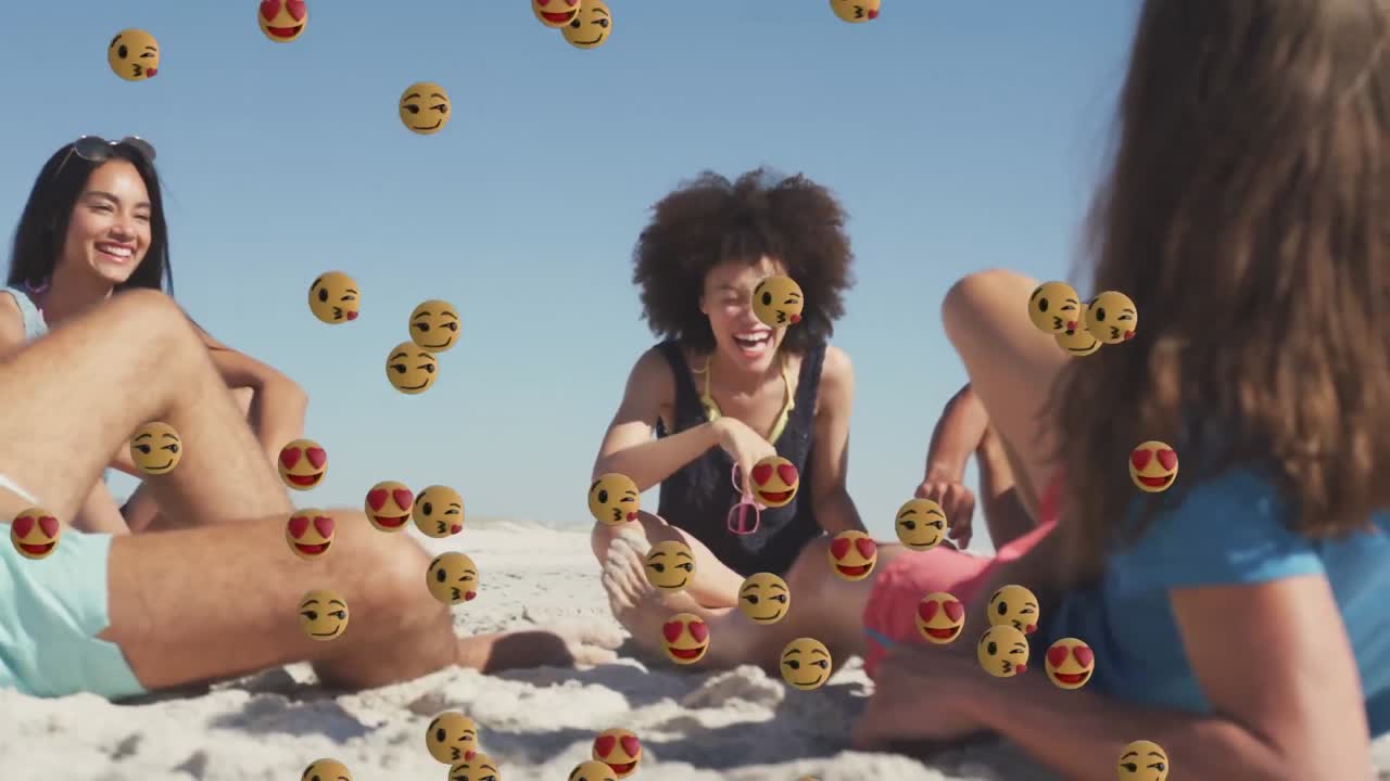 animación de emoji sonrientes y de amor sobre un grupo diverso de amigos felices relajándose en una playa soleada