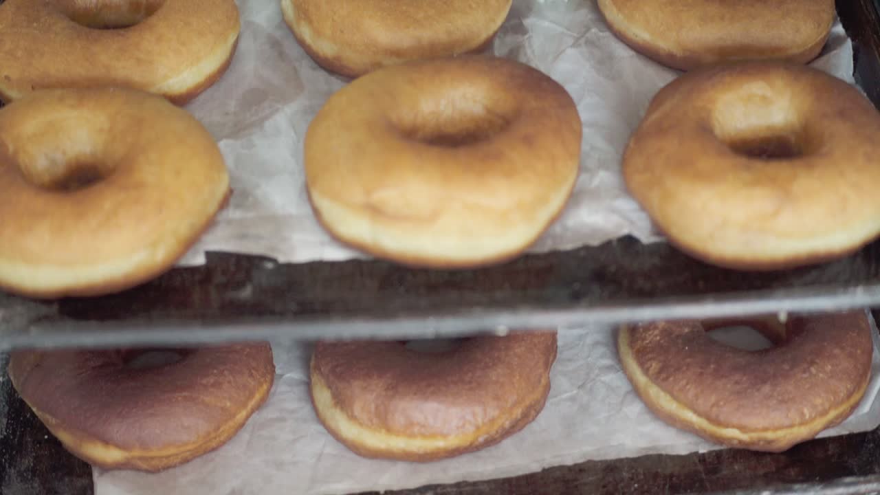 una variedad de rosquillas y pasteles recién horneados que descansan en estantes en una panadería, listos para ser servidos