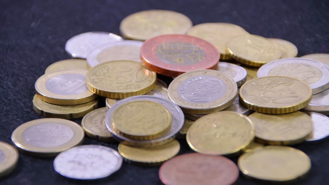 una pila de monedas europeas en un paño negro en una mesa giratoria, primer plano