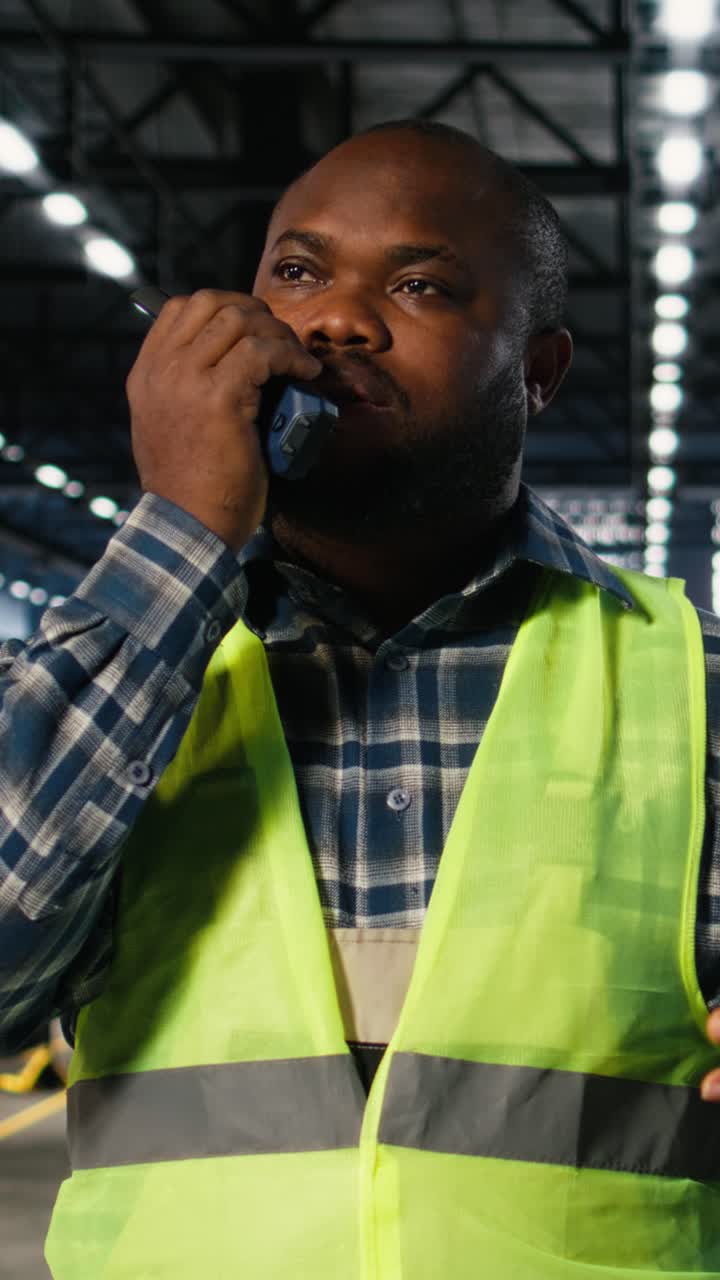 Vertical Video Black engineer talks into walkie talkie and supervising fabrication tools