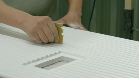 close-up of hand sanding a white cabinet door