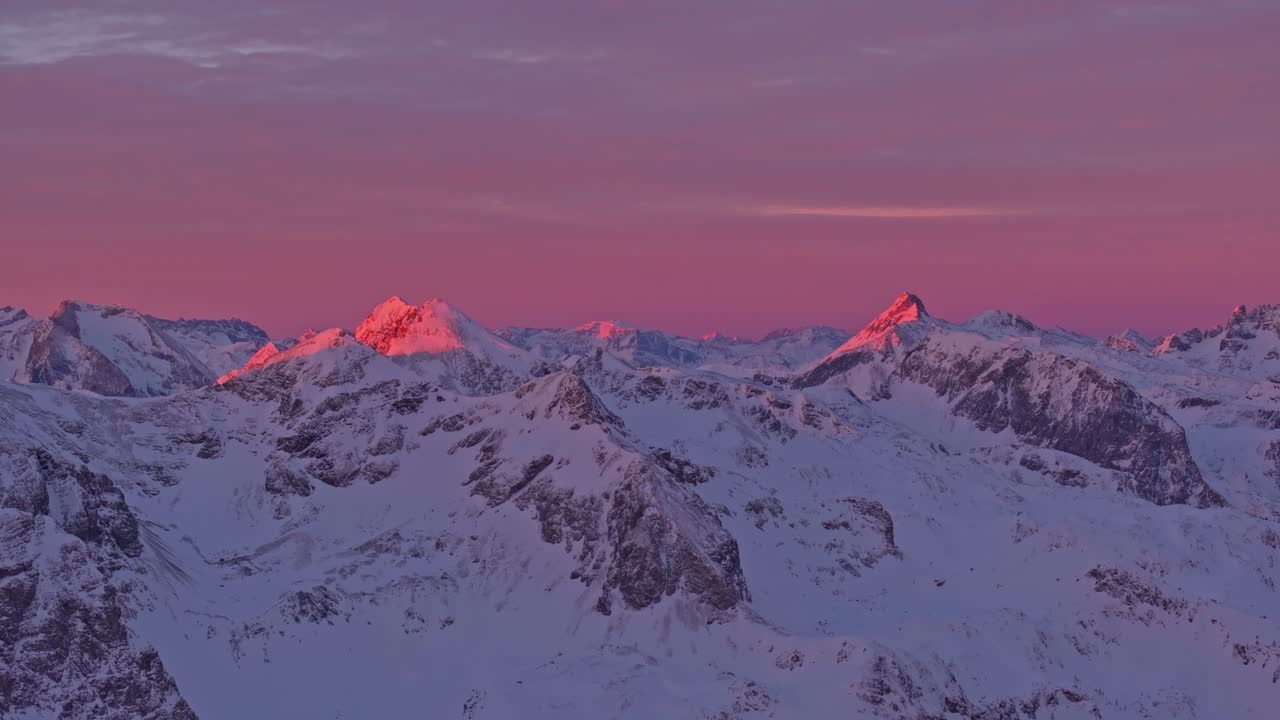 Vista aerea di cime montuose innevate sotto cieli vibranti all'alba in Austria