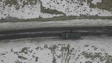 aerial birds eye view of people getting inside black truck parked in snowy roadside landscape