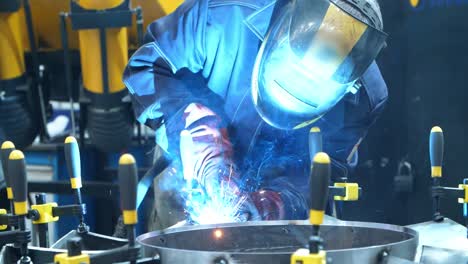 worker in mask carrying out welding of metal billets fastened with manual clips