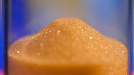 hourglass. super close-up view of sand flowing through an hourglass