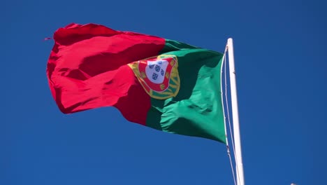 portugal flag waving in the wind with a clear blue sky backdrop