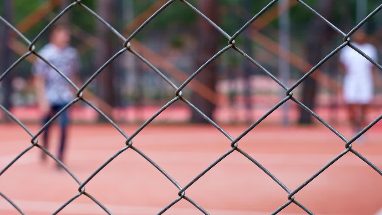 Un giovane uomo di colore gioca a basket con un ragazzo caucasico su un campo all'aperto rosso