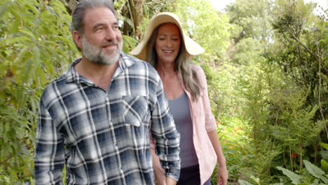 mature couple walking in garden, enjoying nature and smiling together
