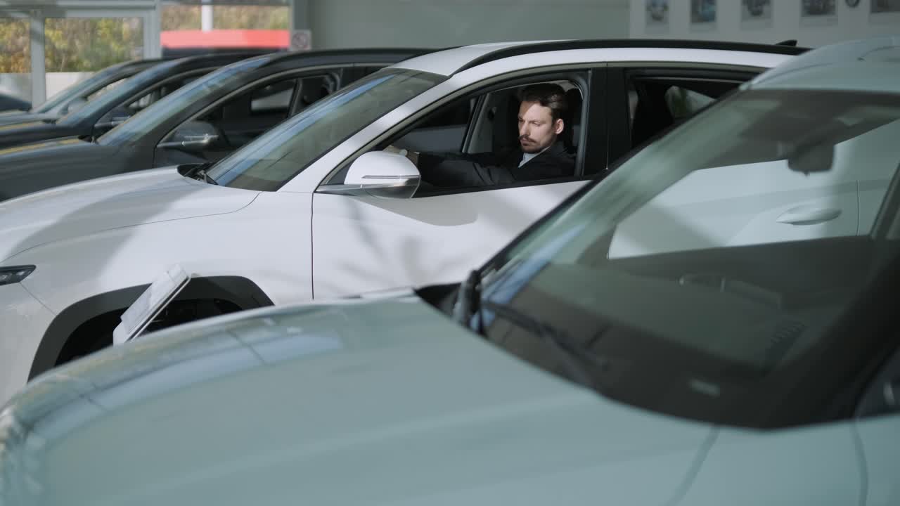 Cars on display in a car dealership with a salesman in one of them