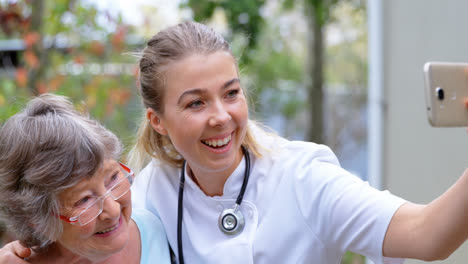 médecin et femme âgée prenant un selfie dans la cour 4k