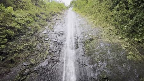 Una-Impresionante-Cascada-Que-Cae-Por-Un-Acantilado-Rocoso-Y-Empinado,-Rodeada-De-Una-Vegetación-Vibrante-En-Oahu