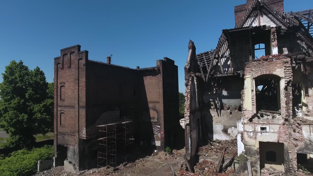 붕괴 된 지붕과 스카포딩이있는 무너지는 벽돌 도살장 건물 중부 유럽의 벽에, 은 여름 날, 4k 드론