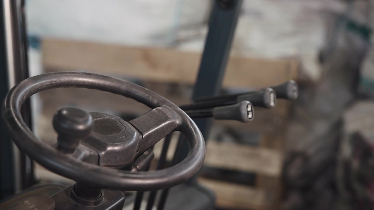 En stillastående metallvev visas i närbild med ett lätt vinklat perspektiv inuti en industriell interiör, med sliten textur, mekaniska detaljer, neutral belysning, gråa toner och ett rent intryck.