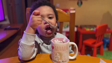 Exotic-and-cute-two-year-old-black-baby,-mix-raced,-eating-homemade-yogourt-by-himself-at-home