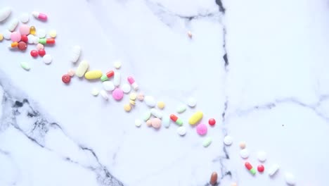 hand pouring out pills from a jar onto a marble surface