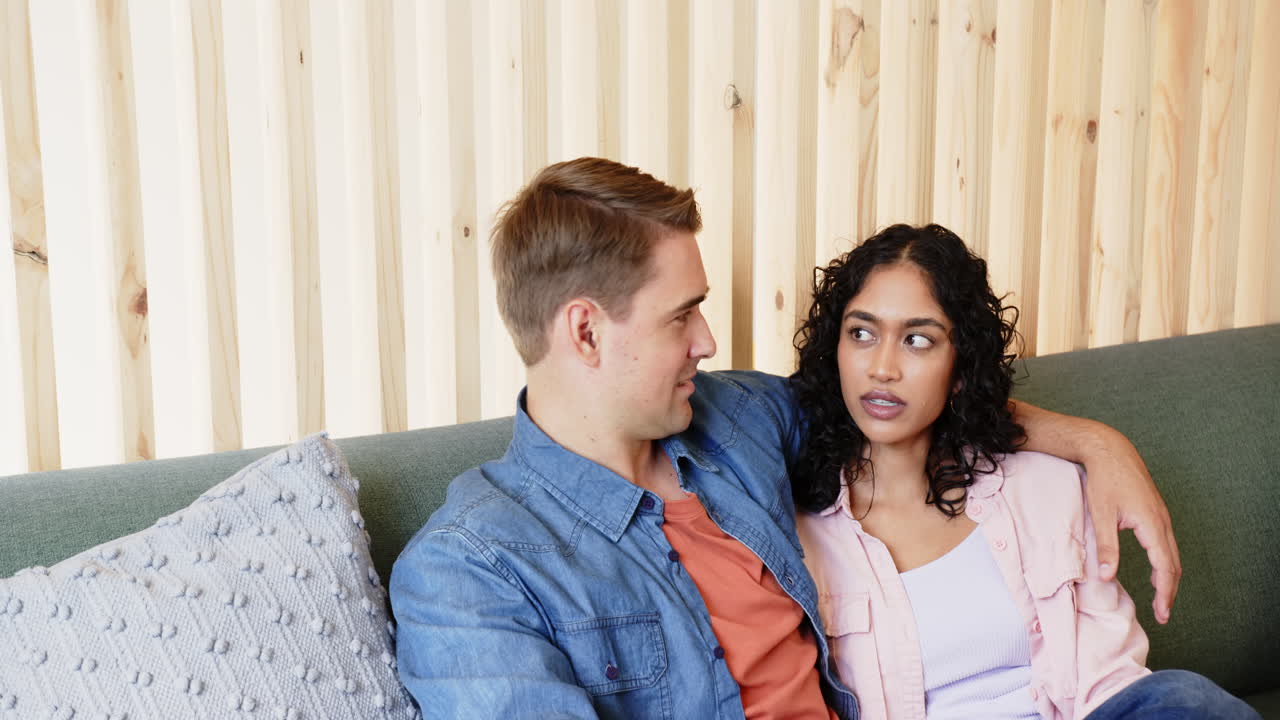 Relaxing on couch, young multiracial couple spending quality time together indoors, at home