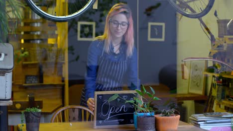 Female-owner-writing-on-chalkboard-in-cafe-4k