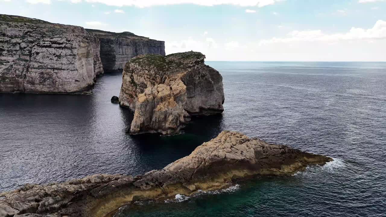 Fungus Rock Il-Ġebla tal-Ġeneral rises in Dwejra Bay San Lawrenz Gozo Malta surrounded by eroded Lower Coralline Limestone cliffs and clear Mediterranean waters within protected coastal landscape