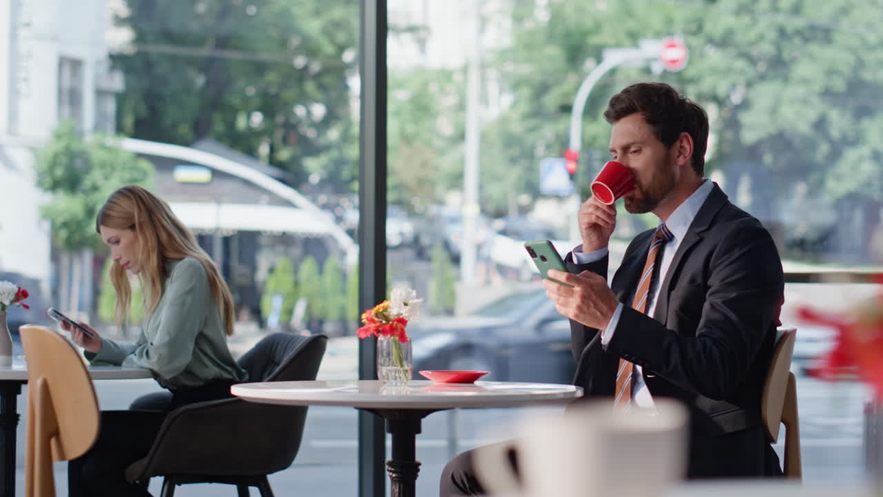Smiling business owner texting cellphone enjoying coffee in modern restaurant