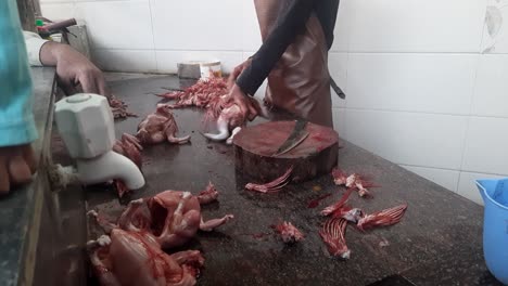 men cutting raw chicken meat at the outdoor workshop in india