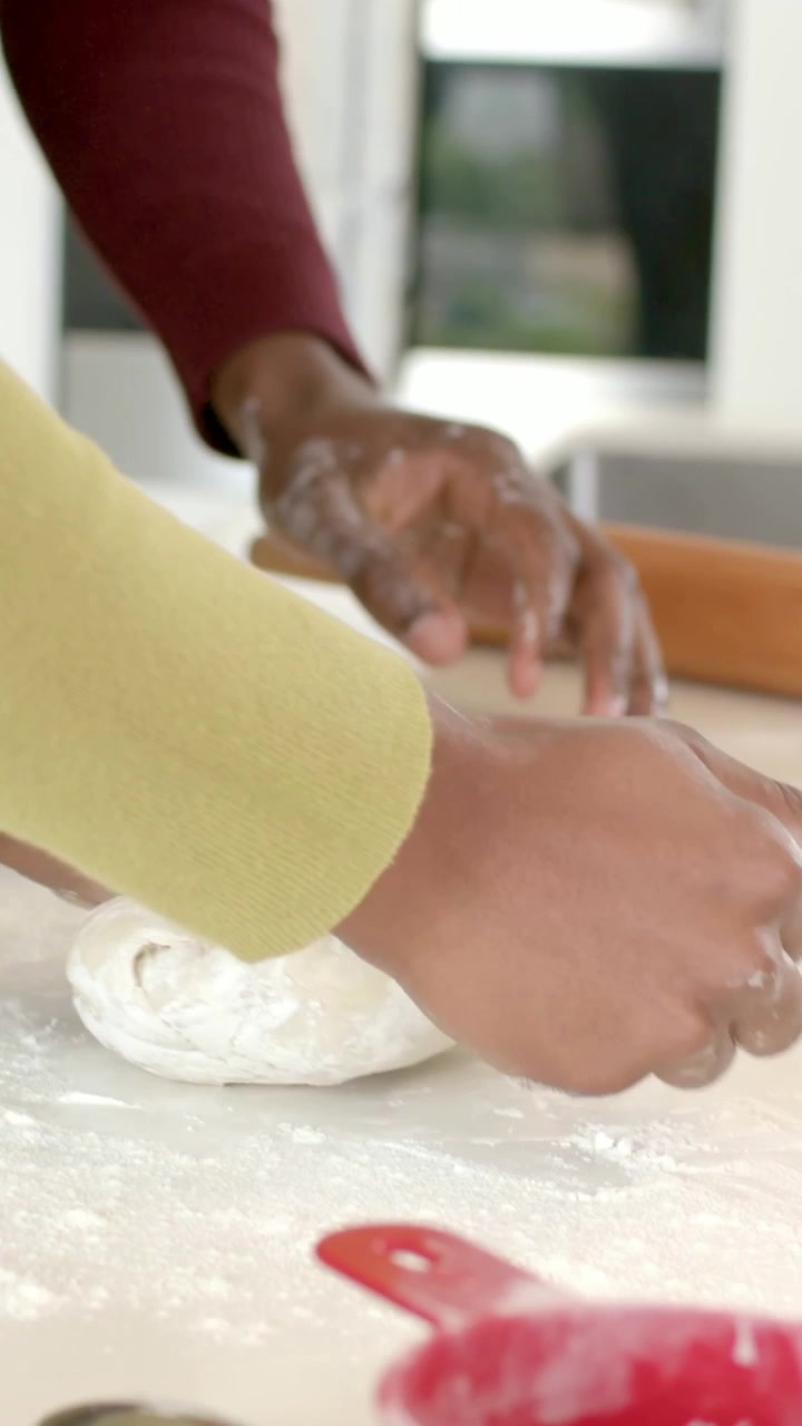 Vertical video: Filming close, couple preparing dough on counter with rolling pin in yellow, maroon