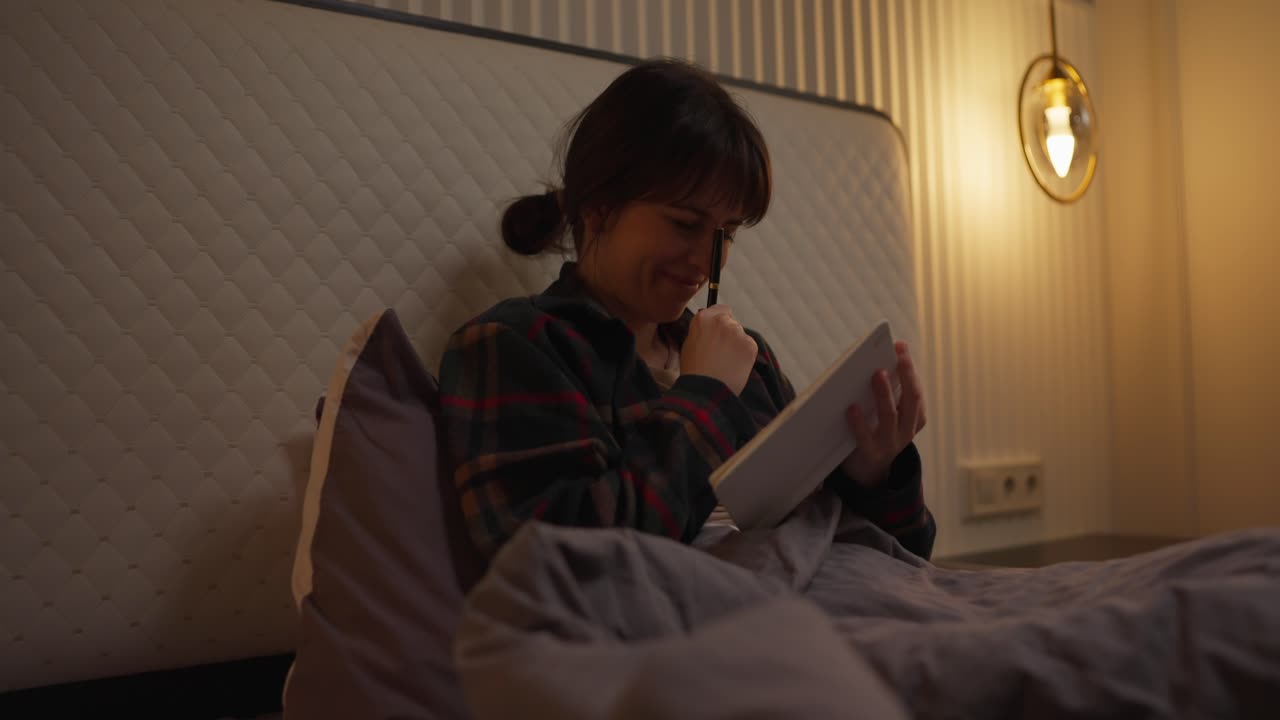 Woman writing in her journal in bed at night