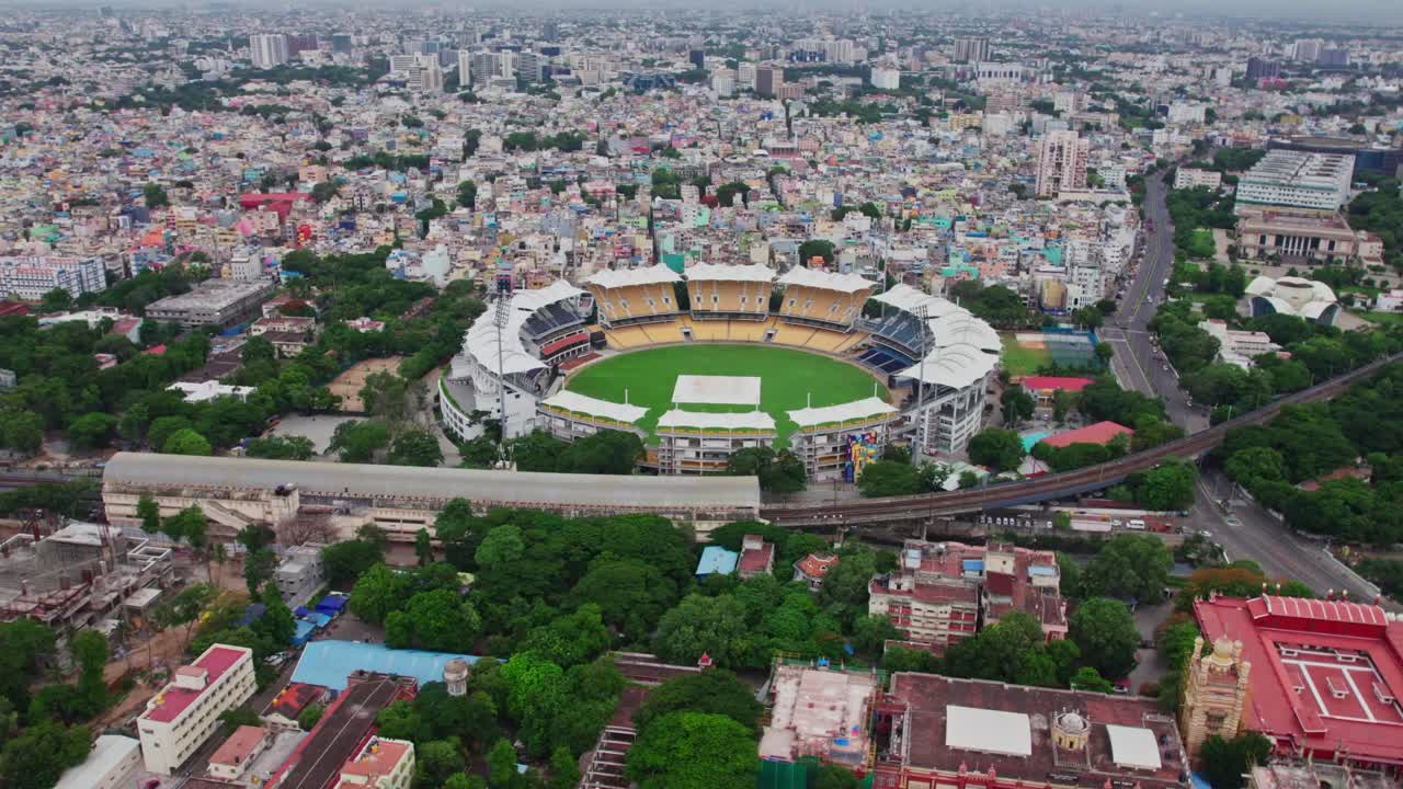 Chepauk railway station with cricket stadium and crowded residential buildings at wallahjah road, chepauk, triplicane, chennai, tamil nadu, india. day time, push in, tilt up, drone shot, 4k.