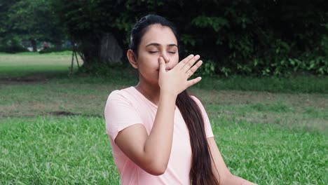 Medium-shot-of-Young-girl-in-sportswear-doing-nasal-or-nostril-breathing-exercise-at-outdoor---concept-of-self-care,-yoga,-workout-and-healthy-lifestyle-at-outdoors-during-coronavirus-covid-19