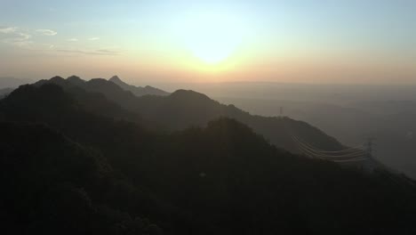 aerial flight showing silhouette of mountain peaks during sunset and golden hour in asia