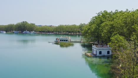 Sanfte-Luftaufnahme-Der-Berühmten-Bootshäuser,-Die-Den-Banyoles-See-In-Katalonien,-Spanien,-Säumen