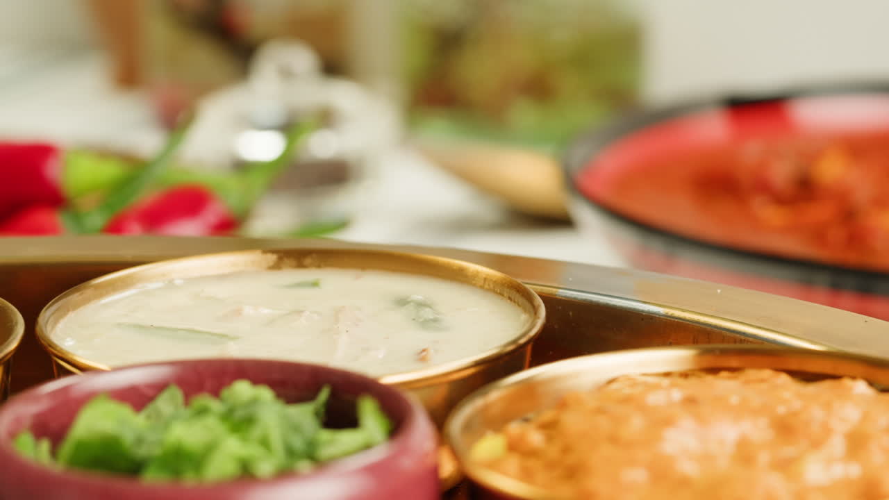 Assorted indian sri-lanka food set on wooden background. Dishes and appetisers of indeed cuisine, rice, lentils, paneer, samosa, spices, masala. Bowls and plates with indian food top view chicken. High quality 4k footage