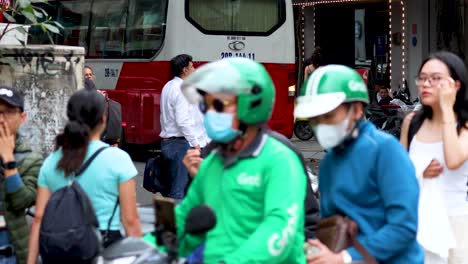 people interacting near parked scooters and a bus