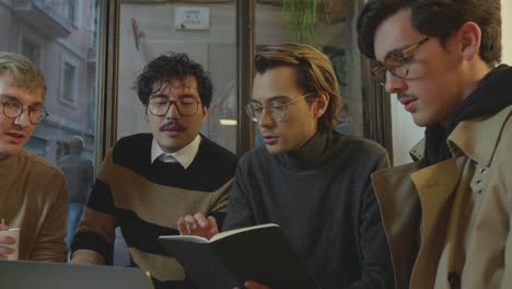 Businessmen-having-conversation-in-cafe.-Guys-looking-on-laptop-screen-indoors