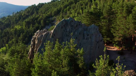 Drone-orbiting-around-a-natural-rock-formation-Eagle's-Rock-Orlovi-Skali,-jotted-with-beehive-like-trapezoidal-niches-on-Rhodope-mountain-in-Bulgaria