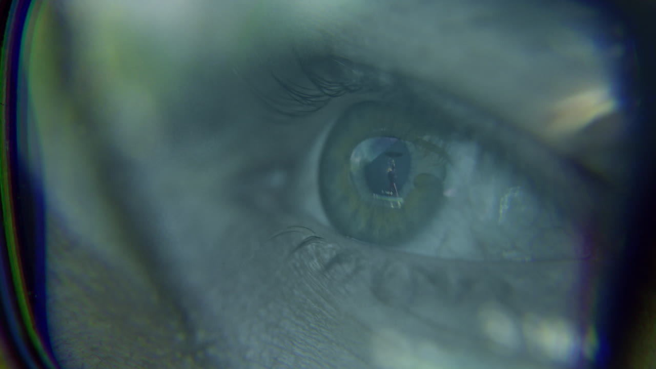 Closeup of a human eye reflecting an image through glasses