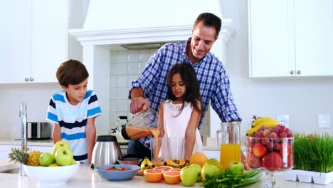 Father-preparing-smoothie-with-his-kids-in-kitchen