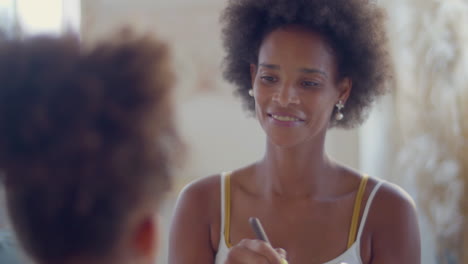 beautiful black woman doing face makeup on her daughter at home