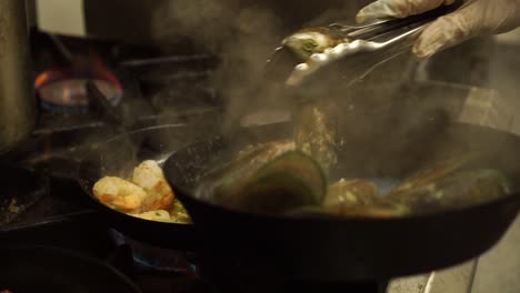 slowmo - new zealand greenshell mussells, salmon, shrimps cooking in kitchen restaurant - close up