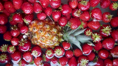 La-Fruta-De-Piña-Y-Fresa-Gira-Y-Luego-Se-Detiene,-Flotando-En-El-Agua