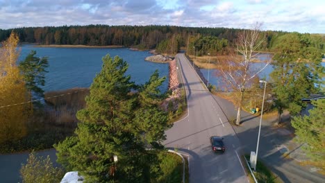 aerial, drone shot, following a car driving on a asphalt road, over a island, in the finnish saaristo, on a sunny, day, in varsinais-suomi, finland